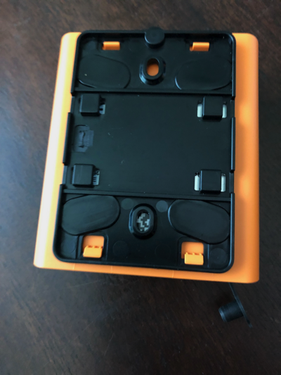 Back panel of a device with black interior and orange frame, showing mounting hooks and connectors.