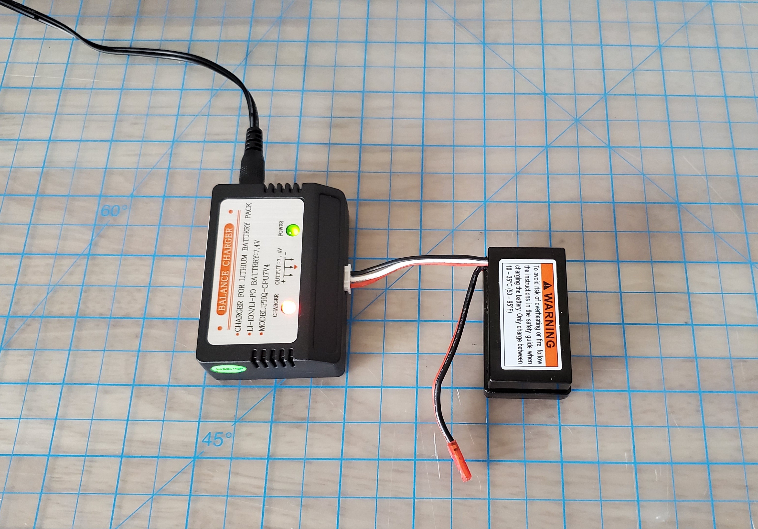 Bild: Die Batterie des Antriebsmoduls des Fahrzeugs ist an das Batterieladegerät angeschlossen, das an eine Steckdose angeschlossen ist.