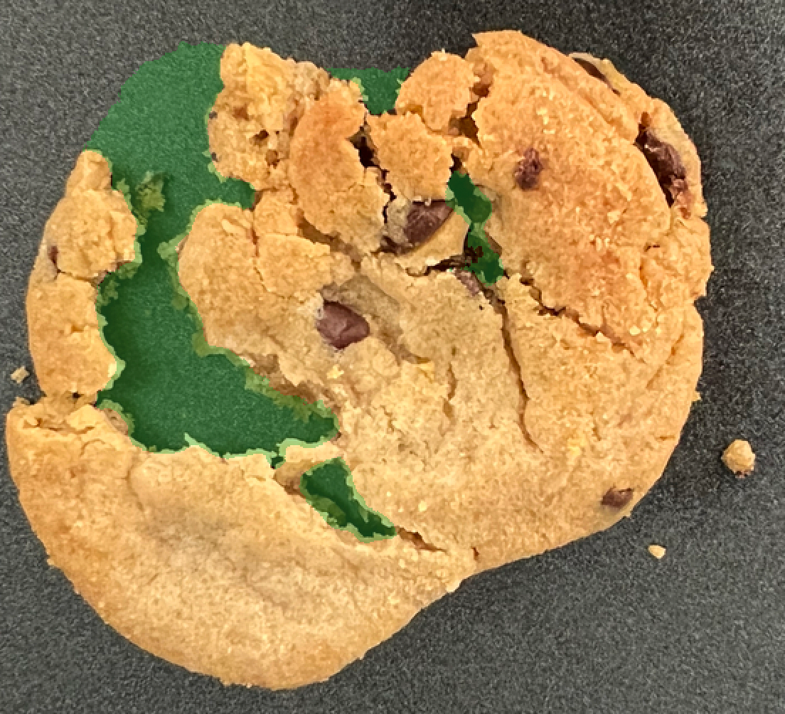 Chocolate chip cookie with a visible crack across its surface on a green background.