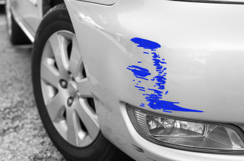 Car exterior with blue paint scratch marks on white body panel near headlight.