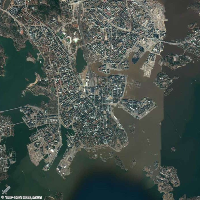 Aerial view of a coastal city with dense urban development, harbors, and surrounding waters.