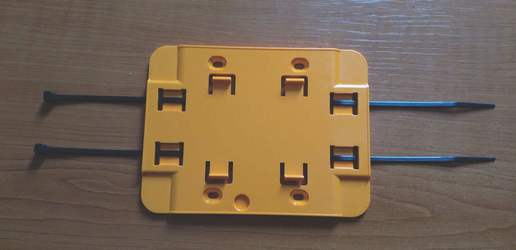 Yellow plastic mounting bracket with cable tie slots and two attached zip ties for securing to non-wall surfaces.