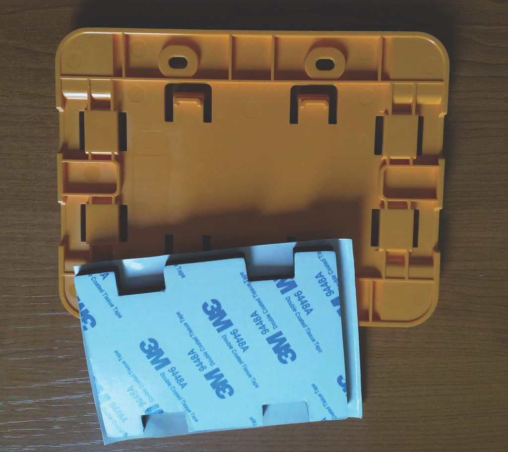 Yellow plastic mounting frame with double-sided tape for secure installation.