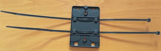 Wall mounting bracket with cable ties threaded through holes for alternative mounting options.